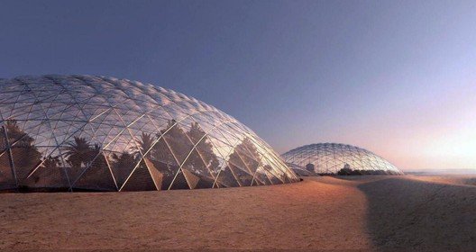 Außenansicht zweier großer Geodesic-Dome in einer Wüstenlandschaft bei Sonnenaufgang. Im Inneren sind Bäume sichtbar.